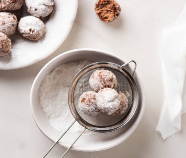 Ev yapımı süzme peynirli çörek topları ve hafif arka planda bir kasede pudra şekeri. Güzel kahvaltı.. 