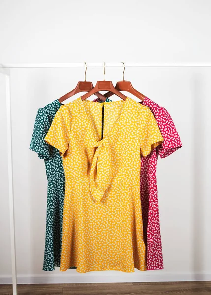 Los vestidos a la moda de los colores verdes, rojos y amarillos que cuelgan de las perchas — Foto de Stock