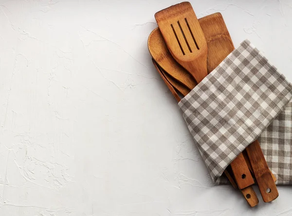 Set of wooden kitchen items in a checkered napkin on neutral grey background. Copy space