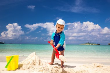 Küçük çocuk kumsalda eğleniyor