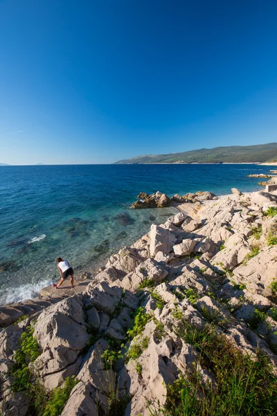 Mujer joven haciendo ejercicio al amanecer en la playa de piedra en Croacia , —  Fotos de Stock