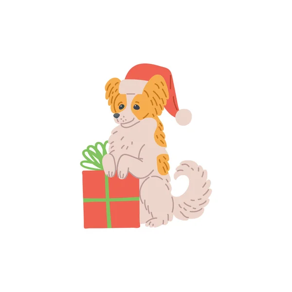Malý pes v červené vánoční klobouk s dárkovou krabičkou plochý vektor ilustrace izolované. — Stockový vektor