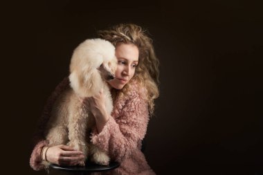 Kıvırcık kız ve kaniş. Sahibine benzeyen bir köpek. Stüdyoda portre