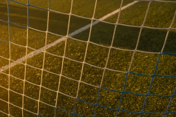 Netting on a football goal in the sunset light on an empty field. Close up.