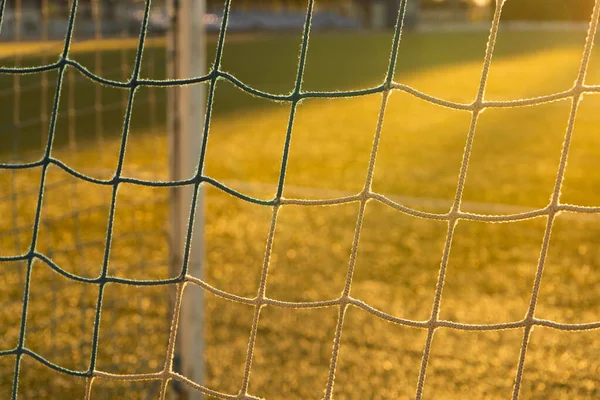 Netting on a football goal in the sunset light on an empty field. Close up.