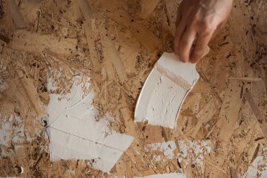 El, macuna spatula sürer. Oyun macunu OSB plakasına uygulanıyor