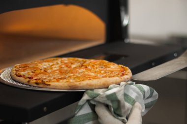 Aşçı pizzayı fırından çıkarır. Fırında peynirli ve domatesli pizza margaritası. Pizzacıda pizza pişirmek.