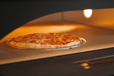 Fırında peynirli ve domatesli pizza margaritası. Pizzacıda pizza pişirmek.