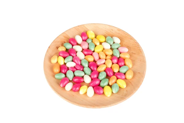 Candy eggs on wooden plate isolated on white — Stock Photo, Image
