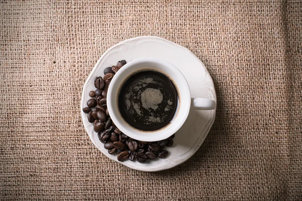 Frischer Kaffee und Kaffeebohnen auf Sacktuch — Stockfoto