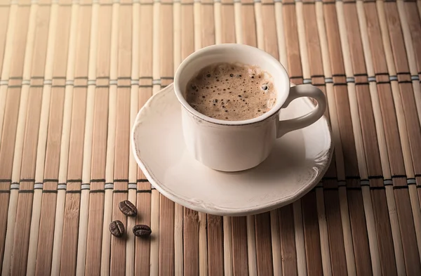 Café fresco y granos de café en una mesa —  Fotos de Stock