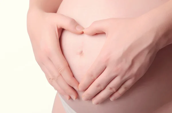 Zwangere vrouw met haar handen in de vorm van een hart op haar baby bu — Stockfoto