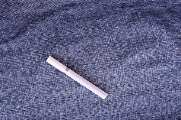 Крупный план фото сигареты на фоне джинсов — стоковое фото