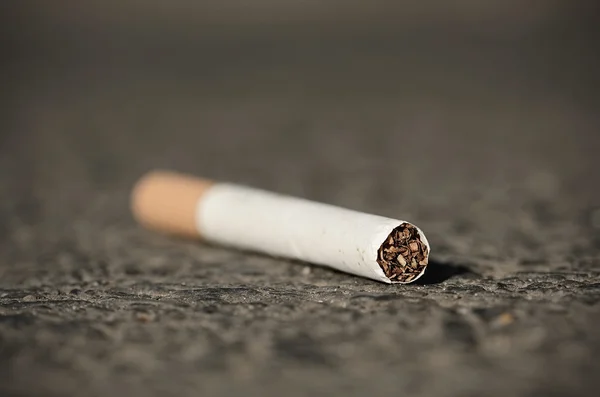 Cigarette on asphalt — Stock Photo, Image