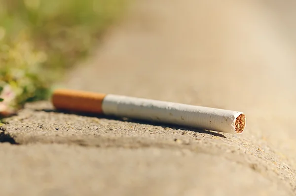 Cigarette on asphalt — Stock Photo, Image