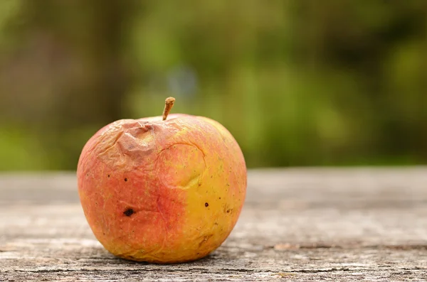 Rotten apple på träbord — Stockfoto