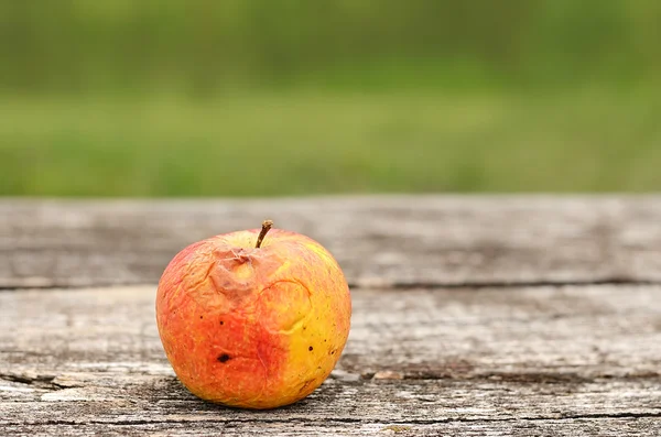 Fauler Apfel auf Holztisch lizenzfreie Stockfotos