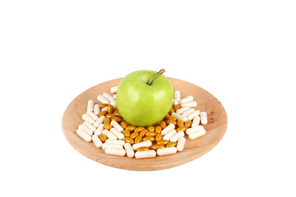 Tabletki na drewnianej tablicy i jabłko na białym tle — Zdjęcie stockowe