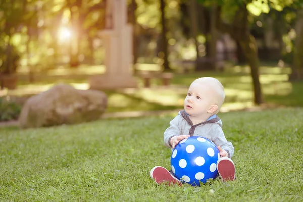 Happy baby sitting in the green grass — Stock Photo, Image