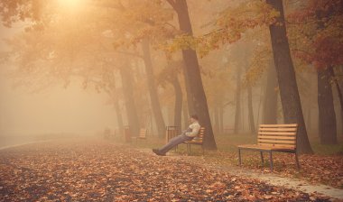 Adam bir sisli gün parkta bankta oturmak