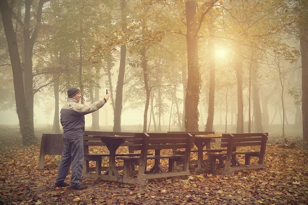 Man tar en bild med sin telefon i skogen — Stockfoto