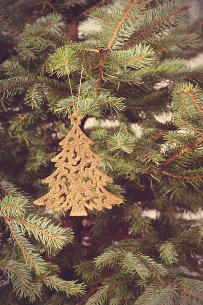 Ouro forma de árvore de natal pendurado no ramo de abeto — Fotografia de Stock