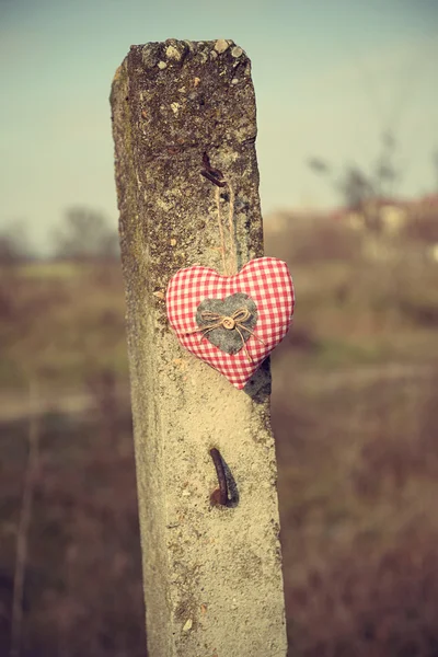 Fabric heart shape hanging on a concrete pillar — Stock Photo, Image