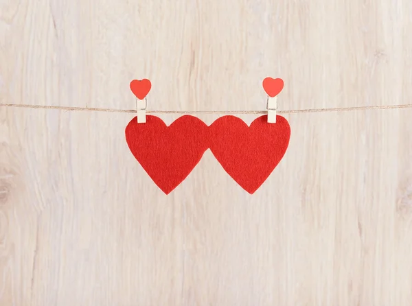 Два красных сердца висят на веревке — стоковое фото