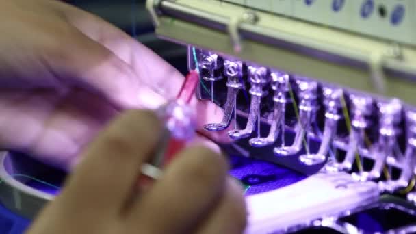 テキスタイルガーメントメーカーの刺繍機の針を変える女性労働者の手 — ストック動画