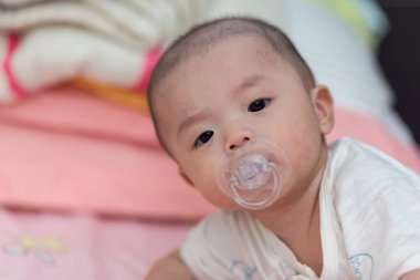 Ağzında emzik olan Asyalı bir bebek.