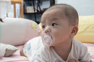 Ağzında emzik olan Asyalı bir bebek.