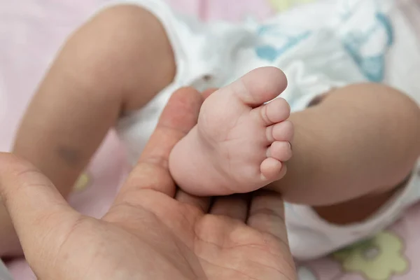 Father holding new born baby boy leg . father taking care of his son kid happy family dream of health