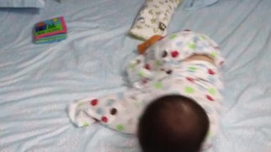 8 aylık Asyalı erkek bebek portresi şaşırtıcı bir şekilde yatakta hareket ediyor.