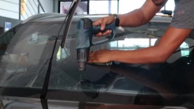 Kota Kinabalu, Sabah, Malezya-29 Aralık 2020: Bir işçi Kota Kinabalu, Sabah, Malezya 'da yepyeni bir arabaya araba camı için renkli bir film kuruyor