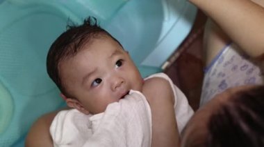 Çinli bir Asyalı anne temiz mendil kullanarak sevimli bir bebeğin yüzünü siliyor.