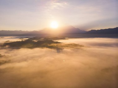Guakon, Sabah, Malezya 'da arka plan olarak güneş ışığı ve sis ve Kinabalu Dağı ile güzel, ahenkli, romantik gün doğumu manzarasının insansız hava aracı görüntüsü