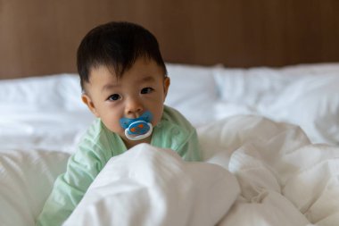 Yatağında emziği olan 10 aylık Asyalı Çinli bir çocuğun portre resmi.