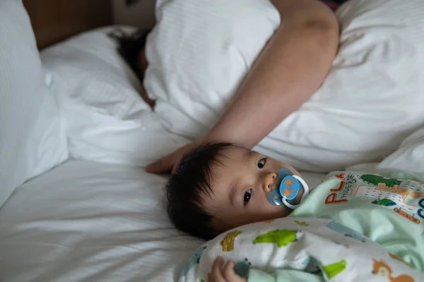 Küçük Asya 'lı çocuk emzik emerek beyaz yatakta uyuyor.