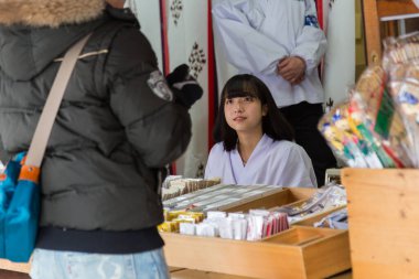 Sapporo, Hokkaido, Japonya-26 Aralık 2017: Japonya 'nın Hokkaido kentindeki Hokkaido Shinto Tapınağı' nda kış mevsimi boyunca bilgi bölümünde oturan güzel genç Japon kız