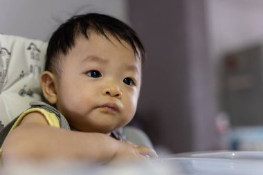 Bebek koltuğunda oturan sevimli, mutlu Asyalı bir Çinli bebeğin portresi.