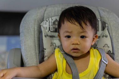 Bebek koltuğunda oturan sevimli, mutlu Asyalı bir Çinli bebeğin portresi.