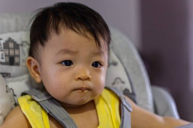 Bebek koltuğunda oturan sevimli, mutlu Asyalı bir Çinli bebeğin portresi.