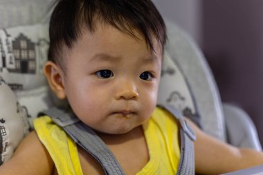 Bebek koltuğunda oturan sevimli, mutlu Asyalı bir Çinli bebeğin portresi.
