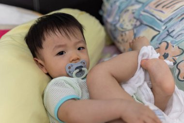 Yatağında emzik emziren tatlı bir erkek bebeğin portresi.