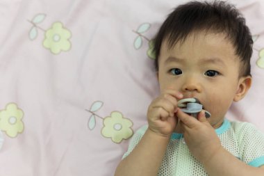 Yatağında emzik emziren tatlı bir erkek bebeğin portresi.