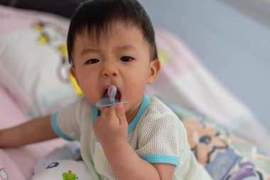 Yatağında emzik emziren tatlı bir erkek bebeğin portresi.