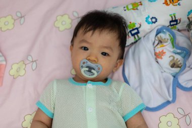 Yatağında emzik emziren tatlı bir erkek bebeğin portresi.