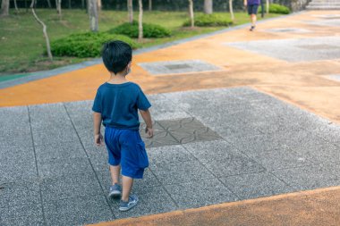 Bir çocuk parkta tek başına yürüyor.