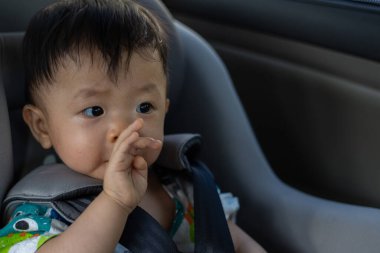 Asyalı Çinli çocuk emniyet koltuğunda arabada oturuyor.