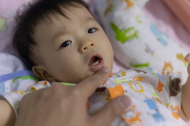 Baba eliyle bebek ağzını kontrol ediyor.